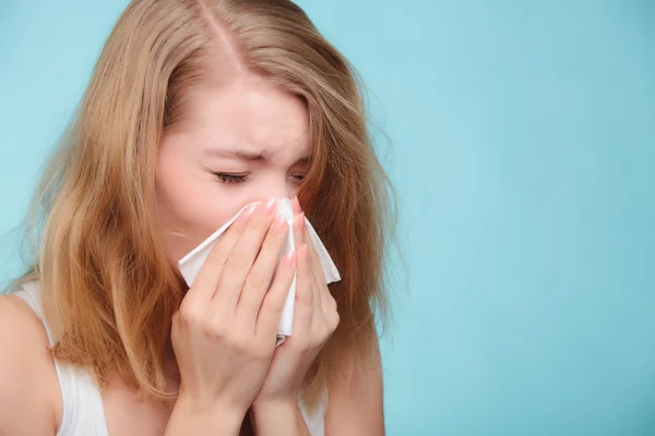 Woman sneezing in tissue.