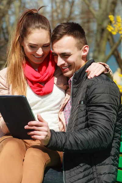 Couple with tablet sitting on bench outdoor