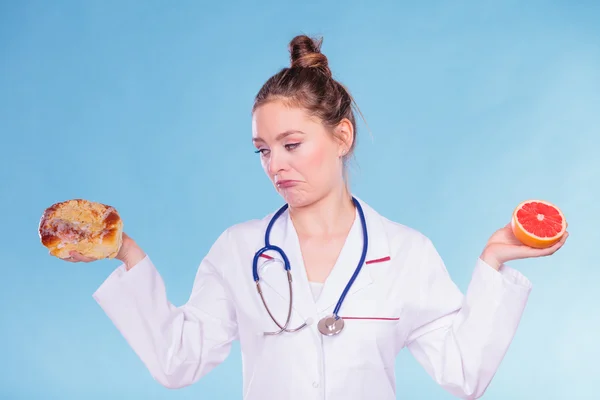 Disgusted dietitian with sweet bun and grapefruit.