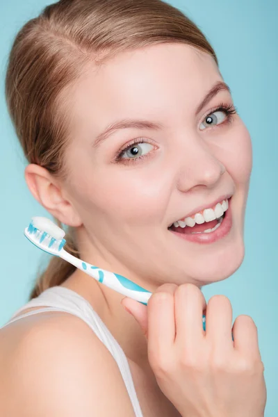 Woman holds toothbrush with toothpaste cleaning teeth