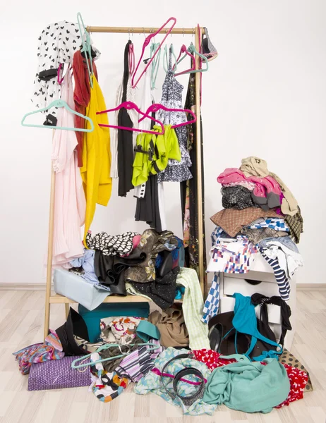 Untidy cluttered woman wardrobe with colorful clothes and accessories.