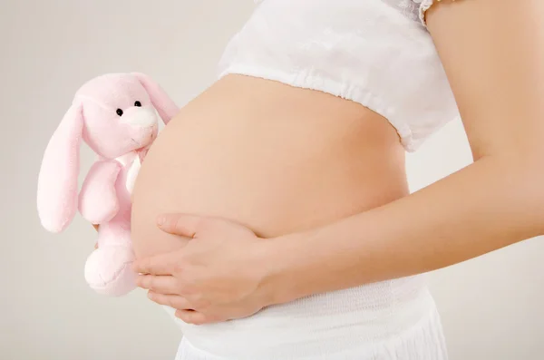 Close up on pregnant belly with toy.