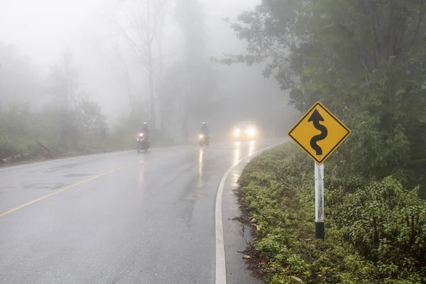 Vehicle driving on curved road in heavy fog