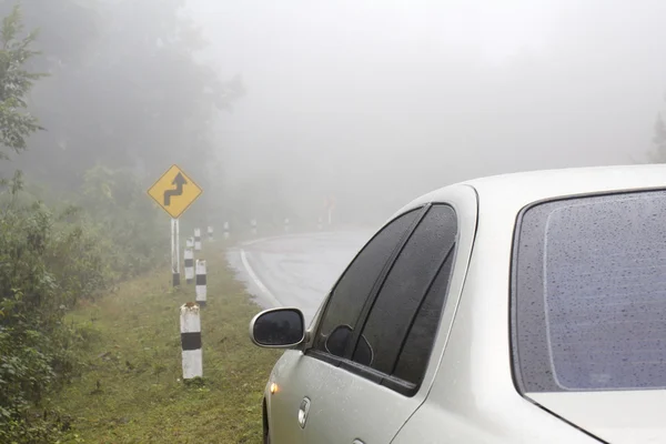 Car on a curve road in rainy and foggy weather