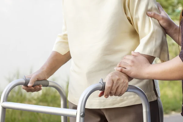 Senior woman using a walker with caregiver