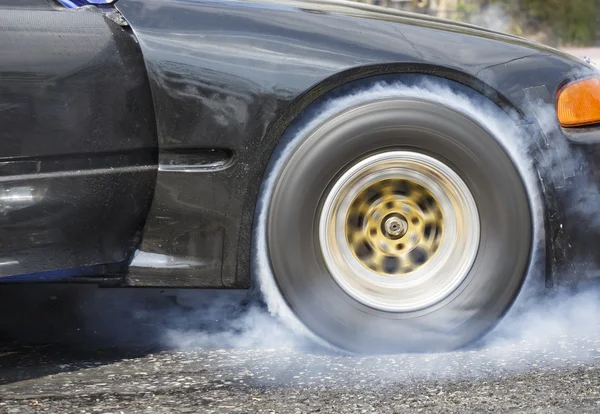 Drag racing car burns rubber off its tires