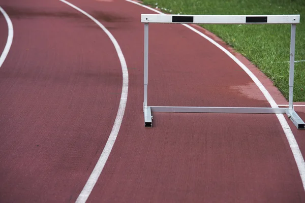 Red running athletic track with hurdle, bad weather, wet