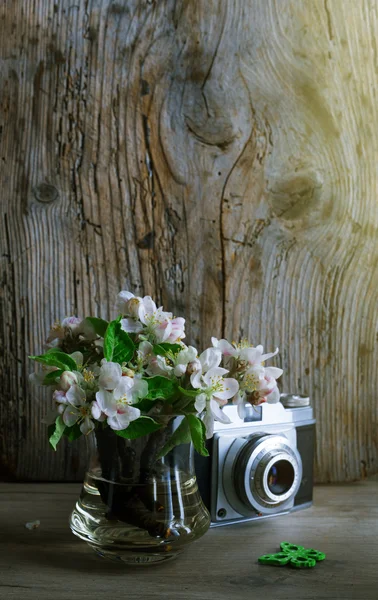 Retro camera with fresh flowers on wooden table