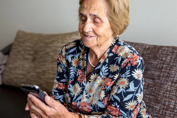 Old smiling woman holding mobile phone
