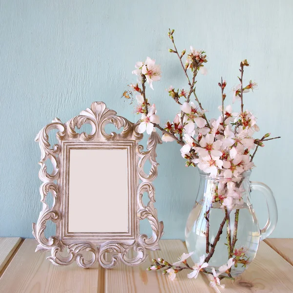 Vintage blank frame next to white spring flowers. selective focus. template, ready to put photography