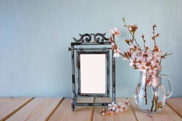 Vintage blank frame next to white spring flowers. selective focus. template, ready to put photography