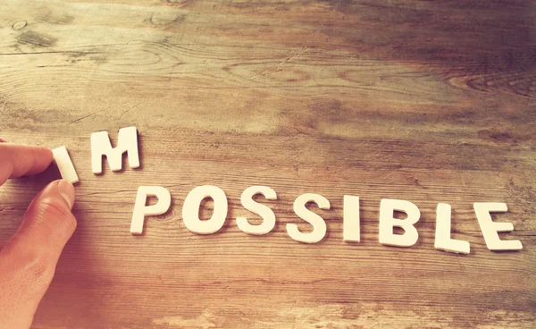 Man hand taking of the letters in from the word imposible so it says possible