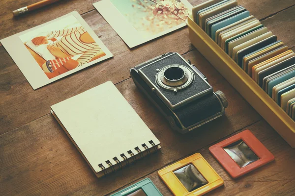 Top view of vintage camera and old slides frames over wooden table background