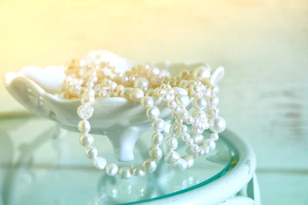High key image of white pearls necklace on vintage table. selective focus