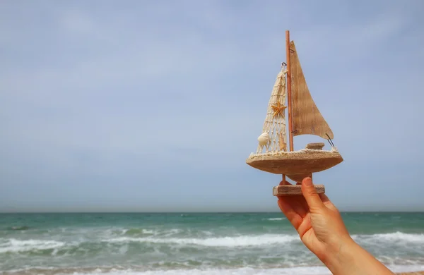 Woman\'s hands holding a boat in front of sea horizon