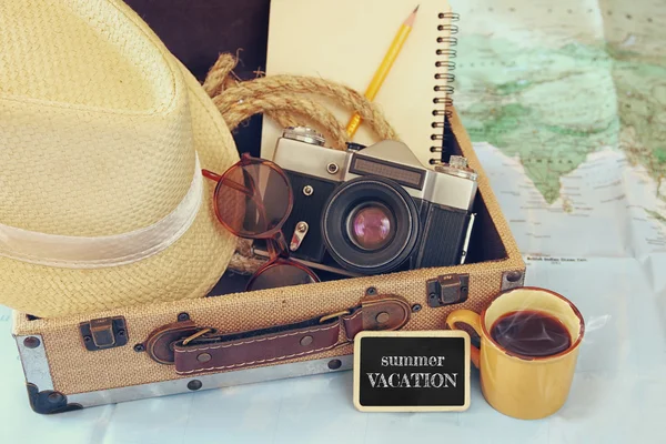Traveling concept. camera, cup of coffee, sunglasses, fedora hut and notebook. vintage filtered. selective focus