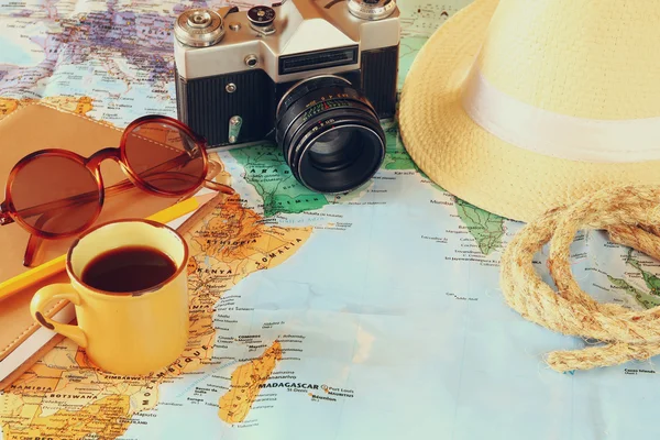 Traveling concept. camera, cup of coffee, sunglasses, fedora hat and notebook. vintage filtered. selective focus