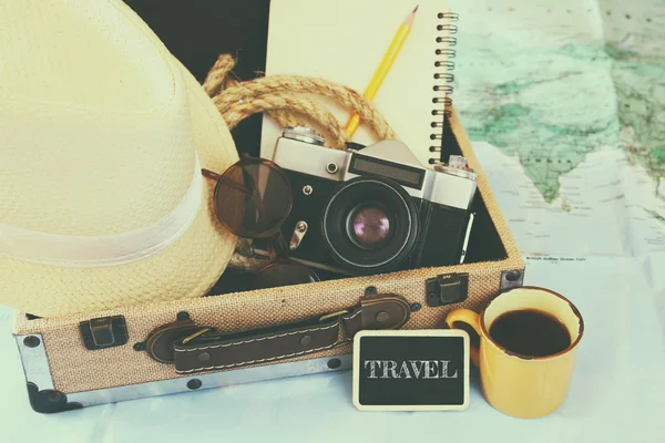 Traveling concept. camera, cup of coffee, sunglasses, fedora hut and notebook. vintage filtered