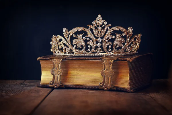 Low key image of decorative crown on old book. vintage filtered.