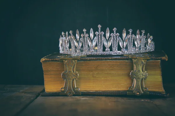 Low key image of beautiful diamond queen crown on old book