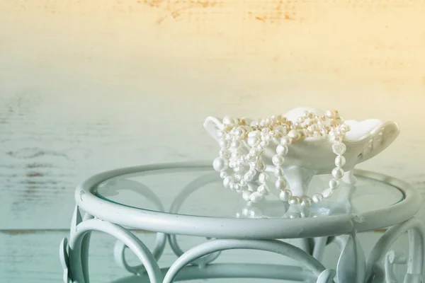 White pearls necklace on vintage table. selective focus