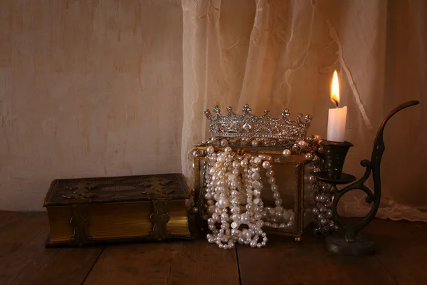 Queen crown, white pearls next to old book