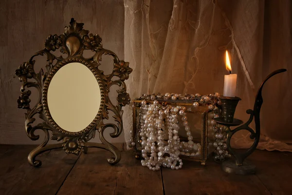 Low key of blank vintage frame, pearls  on wooden table