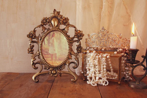 Vintage frame with old photo, pearls on wooden table