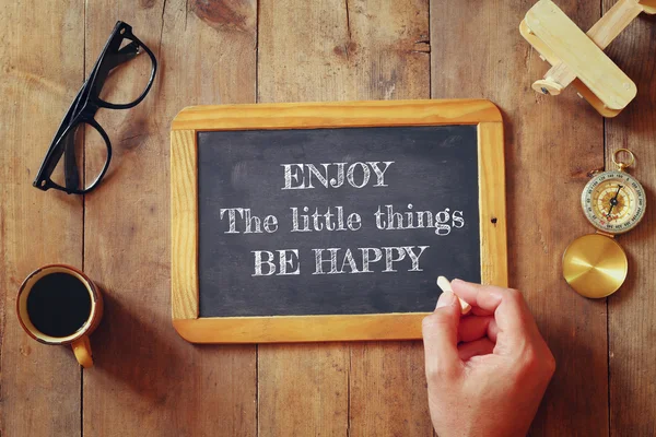 Man writes a phrase: ENJOY THE LITTLE THINGS, BE HAPPY