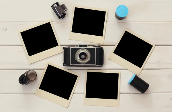 Empty instant photographs next to old camera and film rolls
