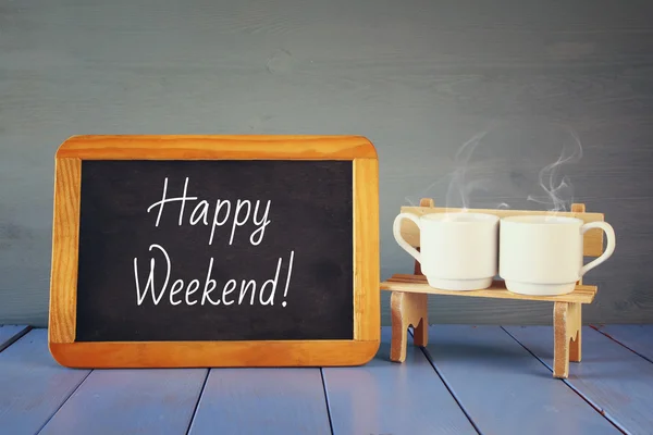 Coffee cups next to blackboard with text: HAPPY WEEKEND