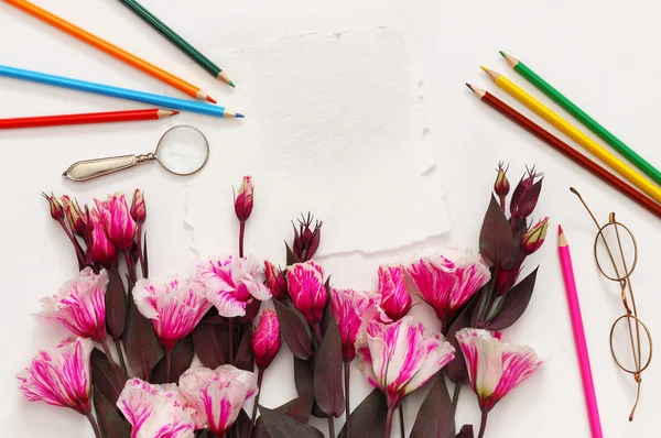 Top view of beautiful pink flowers and colorful pencils
