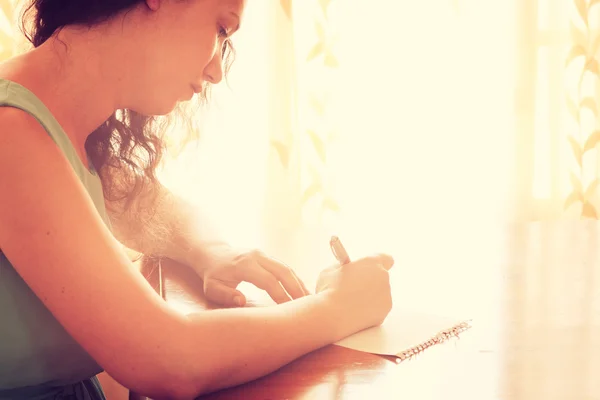 Young woman sitting and writing letter