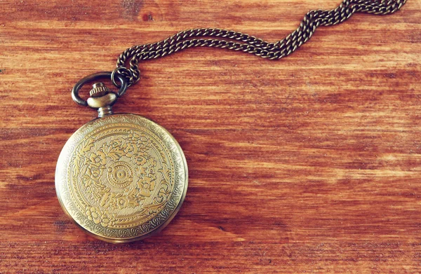Macro image of old vintage pocket watch on wooden table. top view