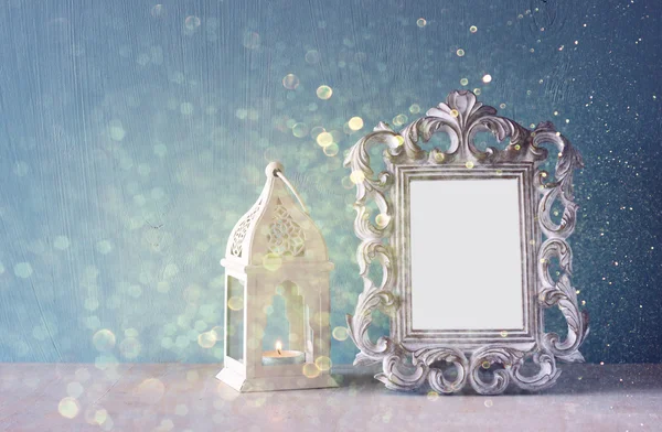 Low key image of vintage antique classical frame on wooden table and glitter lights background. filtered image