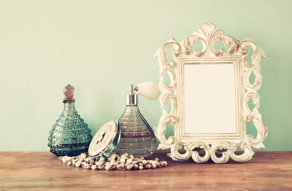 Vintage antique perfume bottles with old picture frame, on wooden table. retro filtered image