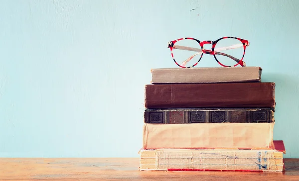 Old books with vintage glasses on a wooden table. retro filtered image