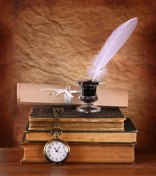 Low key image of white Feather, inkwell and ancient books on old wooden table