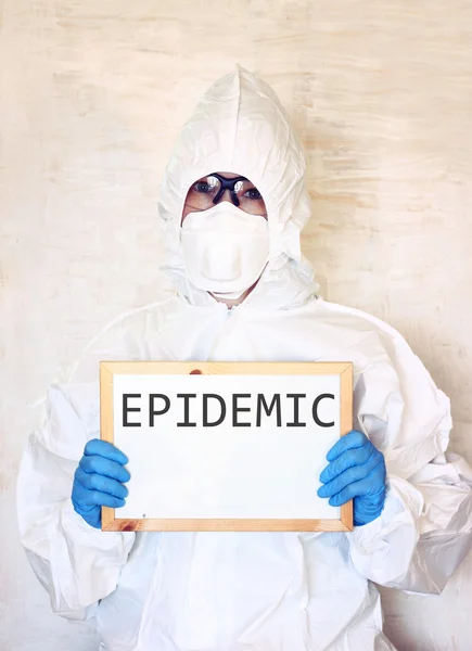 Lab scientist in safety suit holding board with word epidemic