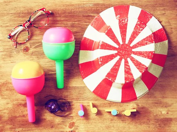 Top view of vintage party accessories - party hat maracas whistles and confetti over wooden board.