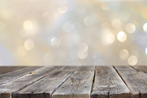 Rustic wood table in front of glitter silver and gold bright bokeh lights