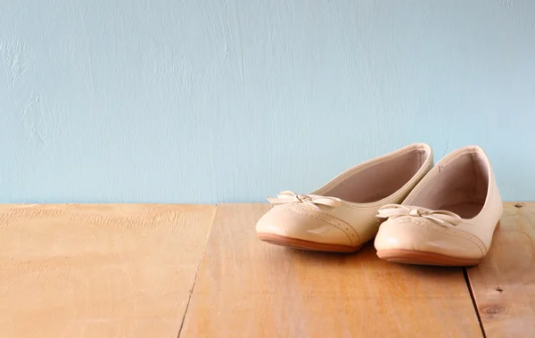 Girl shoes over wooden deck floor.