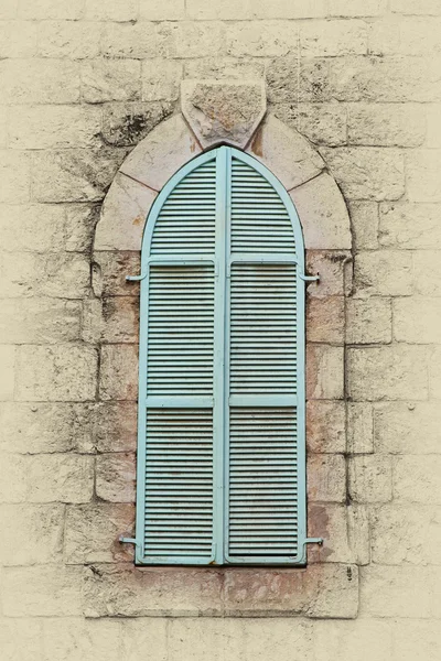 Ancient building\'s wall with blue aqua window shutters