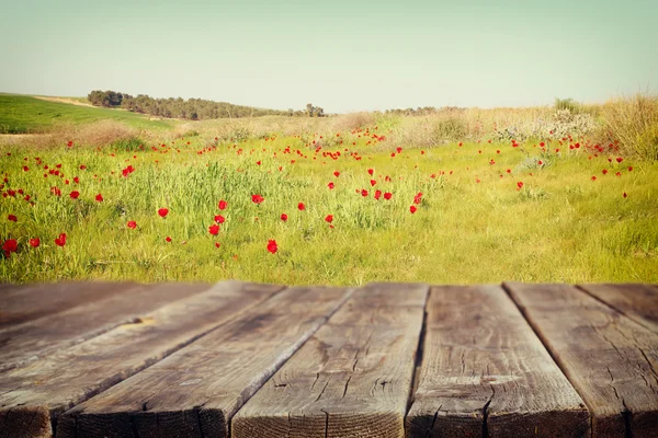 Wood board table in front of summer landscape of field with many flowers . background is blurred