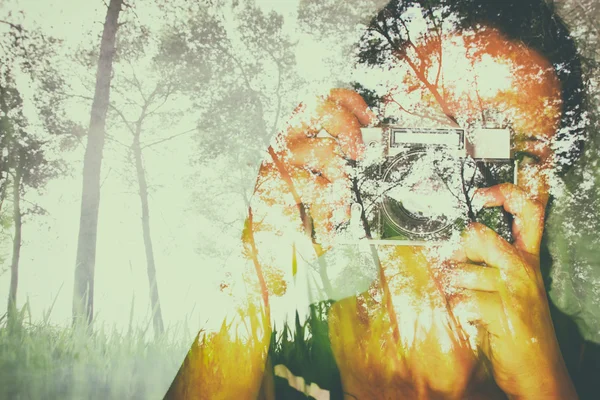 Double exposure image of young girl holding old camera and nature background