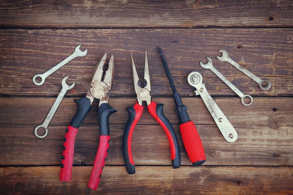 Top view of worn work gloves and assorted work tools over wooden background