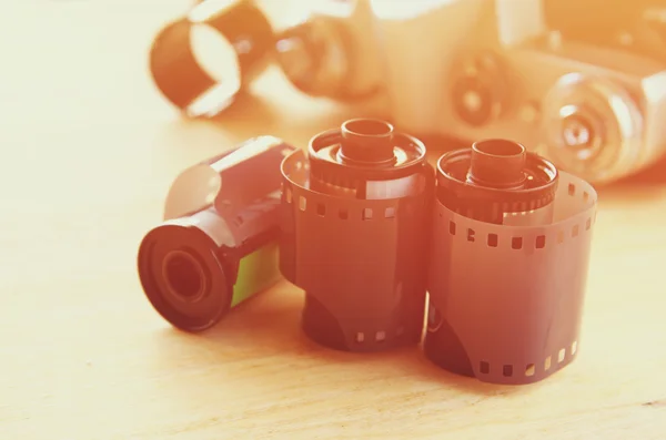 Close up image of film rolls and old camera over wooden table. image is retro filtered