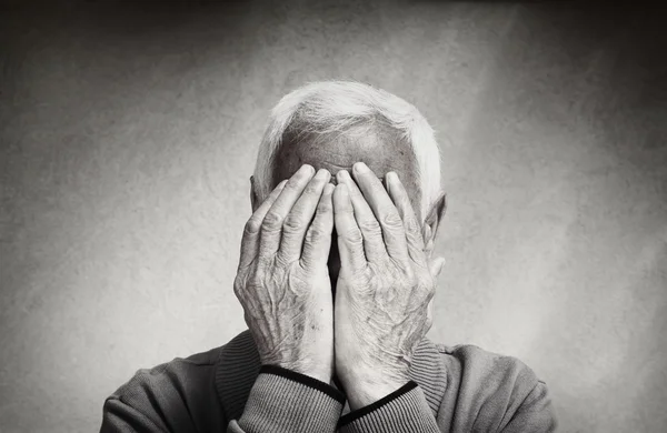 Portrait of senior man covering his face with his hands. black and white image