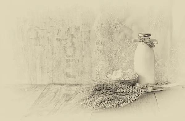 Greek cheese , bulgarian cheese and milk on wooden table over wooden textured background. black and white photo. Symbols of jewish holiday - Shavuot