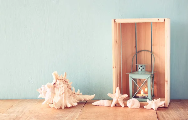 Old nautical  lantern and shells on wooden table over wooden aqua background